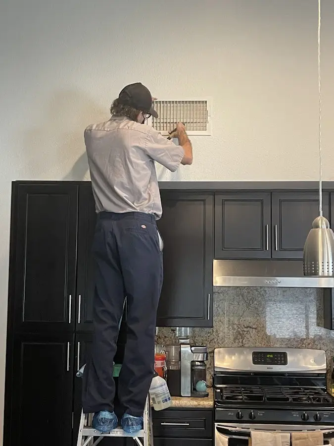 Technician inspecting an air vent during HVAC service in Deerfield